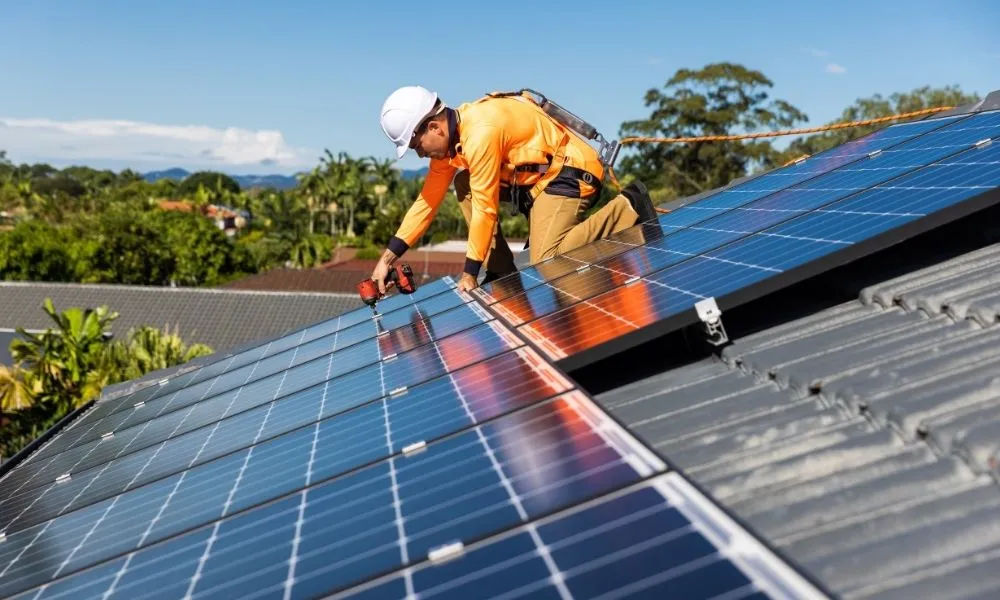 Worker on rooftop installing solar panels